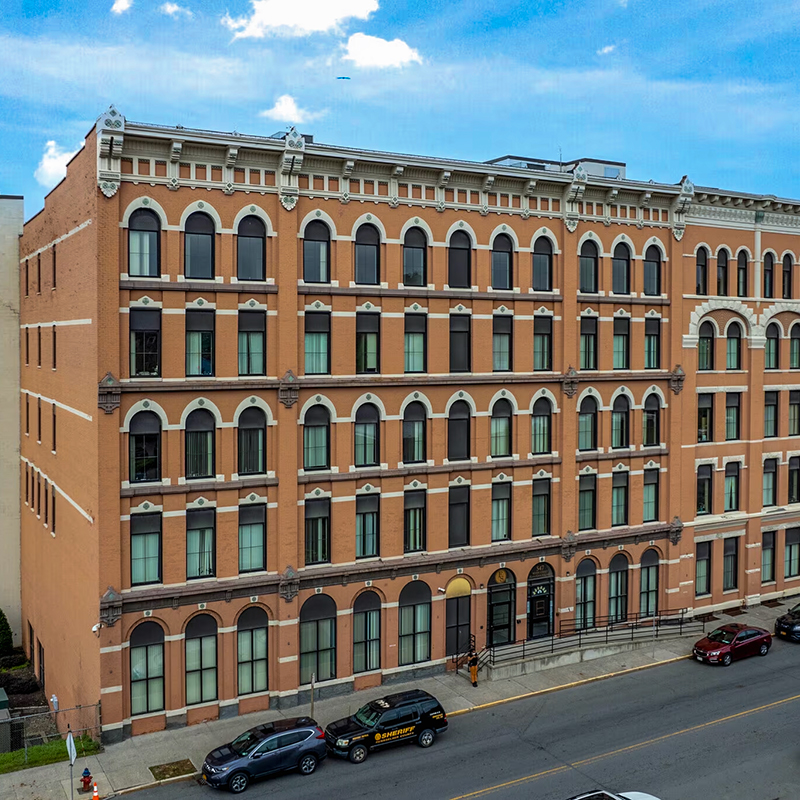 Exterior view of 547 River Street; 7 story office space with orange brick and arched windows.