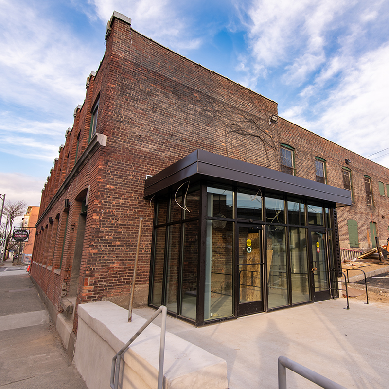 Side view of 558 River Street; glass vestibule connected to brick building.