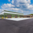 Maintenance shop with three garage bays, a green insulated metal panel exterior and large parking lot.