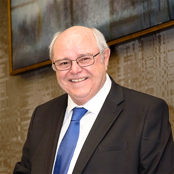 Harold Cring, Member of Bette & Cring, smiling in a black suit with a blue tie.